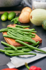 chopped green beans on a wood board with vegetables