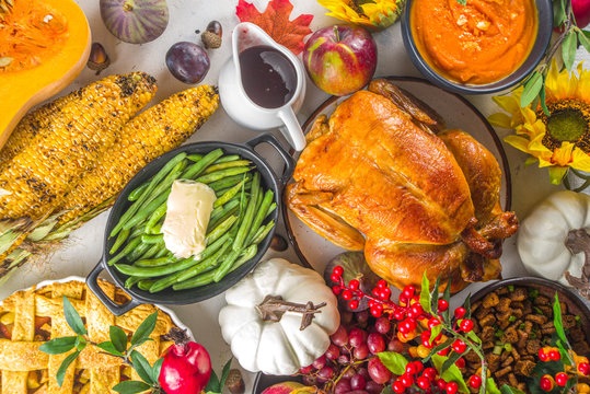 Happy Thanksgiving concept. Thanksgiving day celebration dinner setting with traditional meal and food - green beans, mashed potatoes, cranberry sauce, pumpkin soup, autumn fruits, vegetables