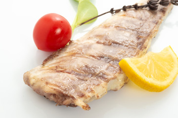 Fish fried on the grill and served on a plate with fresh vegetables