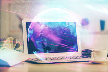 Computer on desktop in office with technology theme hologram. Double exposure. Tech concept.