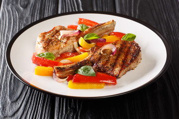 Portion of grilled pork chop with bell peppers, onions and basil close-up in a plate on the table. horizontal