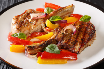 Recipe for spicy grilled pork chop with bell peppers, onions and basil close-up in a plate on the...
