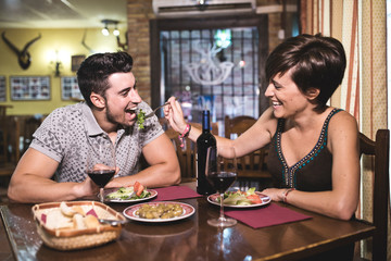 Couple having fun with salad in restaurant. Valentines date