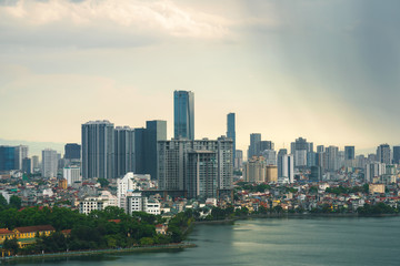 Obraz premium Hanoi cityscape with skyline view during sunset period with dark clouds at West Lake ( Ho Tay ) in 2020