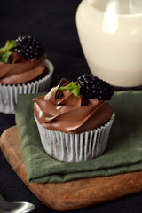 Cupcake de chocolate sobre tabla de madera con fondo negro
