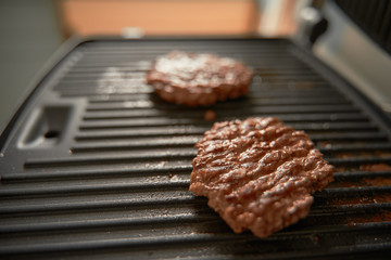 two ground pork burger patties on electric grill ready to eat. copy space for design mockup. fried meat product