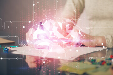 Double exposure of woman's writing hand on background with brain hud. Concept of learning.