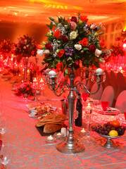 flowers set on a candle stick on a gala dinner table with red background lighting.