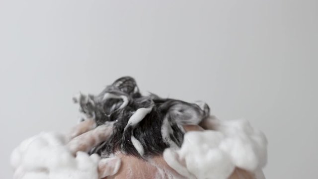 A man washes his head with shampoo on white background, front view