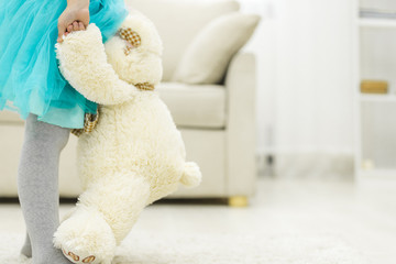 Photo of cropped view of little girl holding teddy bear.