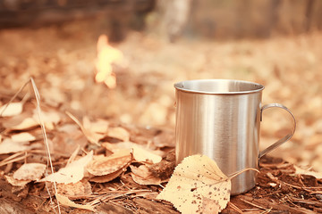 iron mug with hot tea on a camping trip active lifestyle autumn yellow park