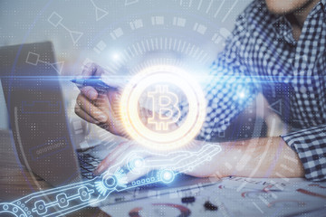 Blockchain theme hologram with man working on computer on background. Concept of crypto chain. Double exposure.