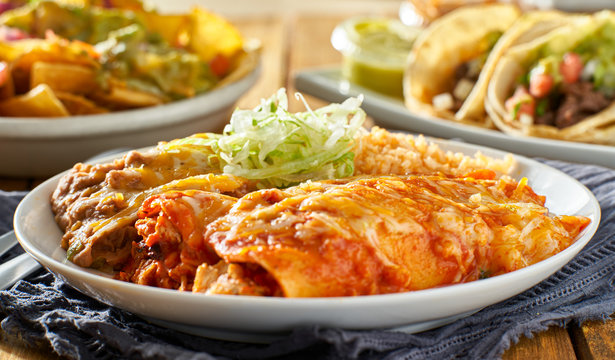 mexican enchilada platter with red sauce, refreied beans and rice