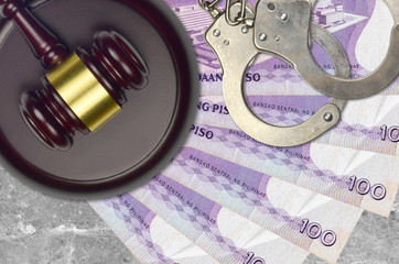 100 Philippine piso bills and judge hammer with police handcuffs on court desk. Concept of judicial...