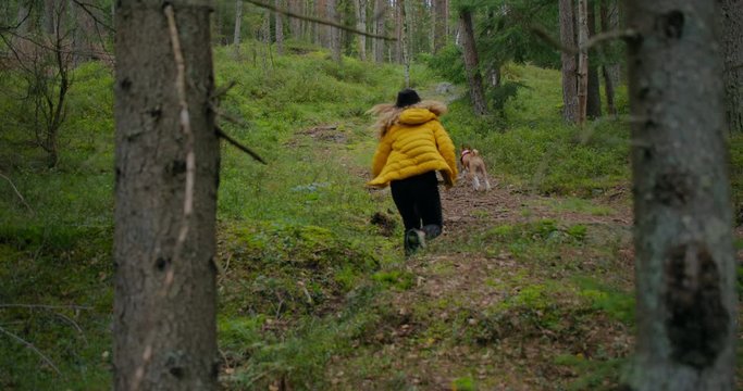 Young woman run on forest trail with her dog, enjoy time outdoors and nature. Weekend adventures with pets in national park. Female hiker walk dog on forest path