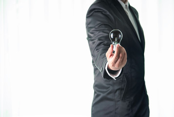 business man hand holding an illuminated light bulb on white background