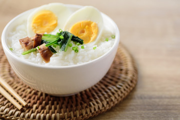 Asian food, Rice soup with boiled egg, grilled mushroom and spinach in a bowl on woven rattan sheet
