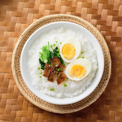 Asian food, Rice soup with boiled egg, grilled mushroom and spinach in bowl on woven bamboo sheets