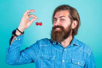 only organic food. dieting and healthy lifestyle. happy bearded man with sweet cherry. cherries for breakfast. cheerful male hipster hold fresh berry. fruit full of vitamin. Green grocery concept