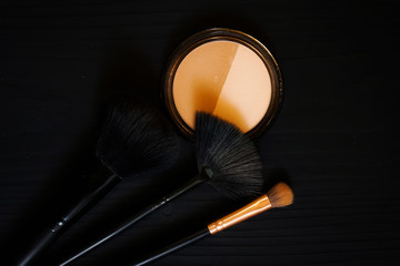 orange sponge and makeup shadow brushes on a dark background