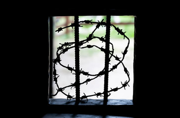 Prison window, opening with bars and barbed wire