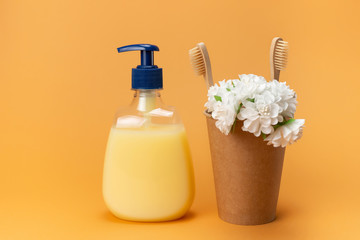 Bottle of liquid soap yellow and bamboo toothbrushes in a cardboard box with a washcloth made of natural material on a beige background. Clean hands concept. Shampoo, Liquid Soap,