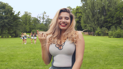 Obraz premium Portrait of beautiful young girl cheerleader smiling and touching hair posing at camera