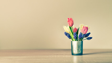 A small vase with freshly cut spring flowers stands on the table.
