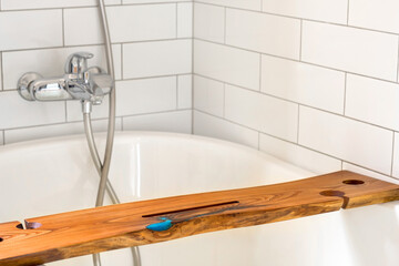 Wooden shelf in white bathtub at home