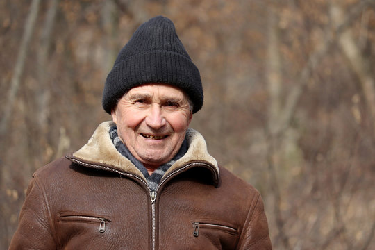 Portrait of happy elderly man standing in autumn park. Concept of old age, life in village