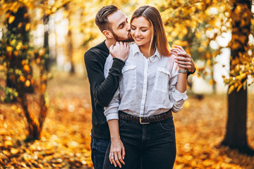 A young couple in love walking in the autumn park on a sunny day