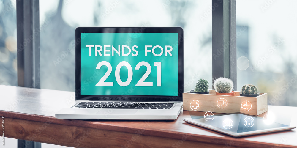 Aufkleber Trends for 2021 in laptop computer screen with icon floating on tablet on wood stood table in at window with blur background,Digital Business or marketing trending