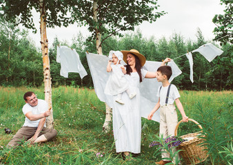 Happy young big family near the clothesline in the village on a summer day