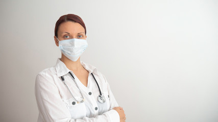 Confident woman doctor wearing medical mask standing with crossed arms. 