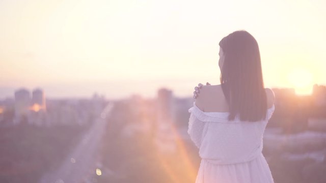 Young female in dress enjoying cityscape at sunset, dreaming woman, solitude