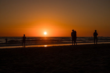 Fototapeta na wymiar Silhouettes of people taking photos at sunset on the beaches of Cadiz, Spain