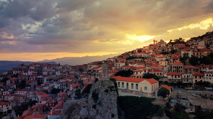 Aerial drone photo of beautiful sunset with golden colours and clouds over clock tower in picturesque and traditional village of Arachova, Viotia prefecture, Greece