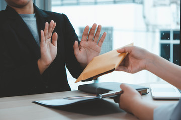 The concept of anti-bribery and corruption. Businessmen refuse and do not receive money banknote offers from businessmen to accept the contract terms of the investment agreement.