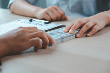Bribery and corruption concept, bribe in the form of dollar bills, Businessman giving money while making deal to agreement a real estate contract and financial corporate.