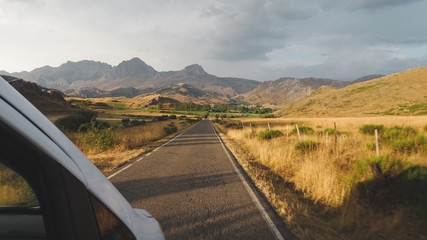 Furgoneta por carretera rural al atardecer con las Ubiñas y San Emiliano de fondo