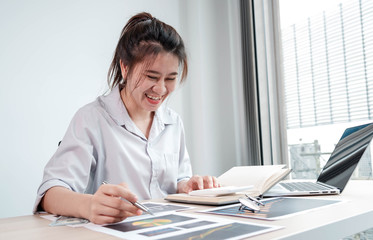 Portrait beautiful asian businesswoman working in her home, office, looking at graphs, financial markets, her business, and paying much attention.