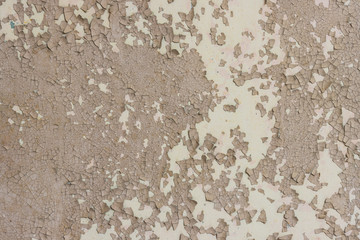 Peeling paint on the wall. Old concrete wall with cracked flaking paint. Weathered rough painted surface with patterns of cracks and peeling. Grunge texture for background and design. High resolution.