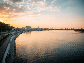 Fototapeta premium Sunset cityscape in Kyiv, Ukraine. Poshtova square in Kiev. Landscape view of the Dniper river against golden hour skies