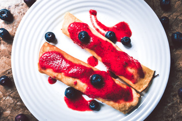 Pancakes with white cheese and strawberry mousse served on a plate.