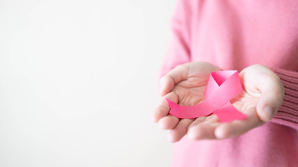 Breast Cancer Awareness Month in October. Close up of female hands holding pink ribbon awareness...
