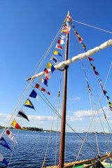 Sea signal flags mounted on the mast against the blue sky, taken close-up. Ship's flags fluttering in the sky. Signals, Morse code. Flagpole.