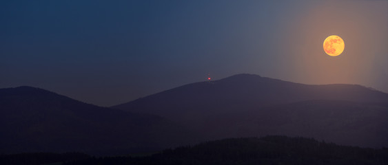 The full flower moon - May, 07, 2020. The rising moon over the mountain peaks of the Sudetes.