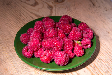 Raspberries on a plate and a wooden table