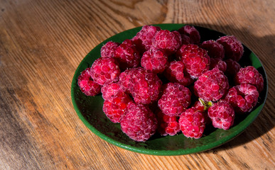 Raspberries on a plate and a wooden table