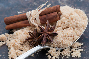 Close up shot of Star Anise, Brown Sugar and Cinnamon Sticks on a textured Black Background